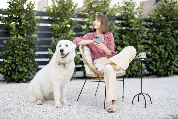 年轻的女人和她那只硕大的白色可爱的狗坐在一起很放松 在后院共度时光 与宠物的友谊和户外快乐的闲暇时间概念 — 图库照片
