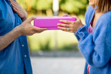 Man gives a gift to his woman, close-up on a pink box. Celebrating anniversary, thanksgiving day, valentine or birthday concept