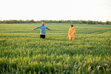 Kaygısız çift gün batımında yeşil bir alanda yürürken eğleniyor. İnsanlar yaz mevsimini tarım arazilerinde doğanın tadını çıkararak geçirirler.