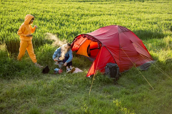 年轻夫妇一起做饭 在绿地上的营地度过夏天 男人和女人带着大自然的帐篷旅行 — 图库照片