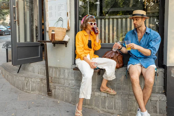 年轻时髦的一对朋友坐在旧城街道上现代咖啡馆的窗台前 一起出去玩 咖啡馆风格和闲暇时间的概念 — 图库照片