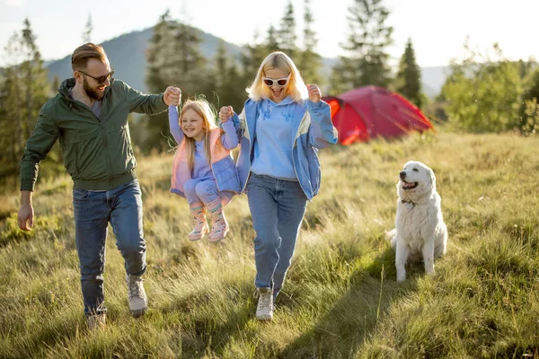 一对带着小女孩和小狗的年轻的高加索夫妇在高山上与帐篷一起旅行的过程中度过了一段快乐的闲暇时光 在营地度过一个快乐的家庭暑假 — 图库照片