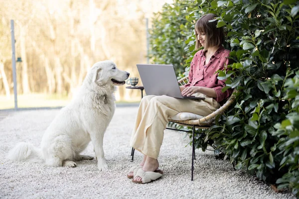 Genç Bir Kadın Dizüstü Bilgisayarda Çalışırken Arka Bahçede Sevimli Köpeğiyle — Stok fotoğraf