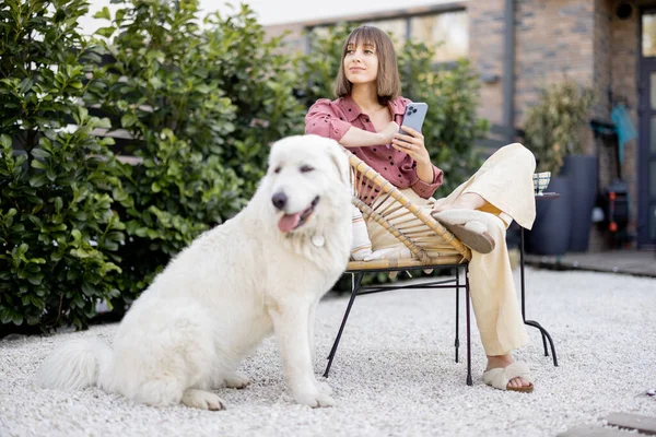 年轻的女人和她那只硕大的白色可爱的狗坐在一起很放松 在后院共度时光 与宠物的友谊和户外快乐的闲暇时间概念 — 图库照片