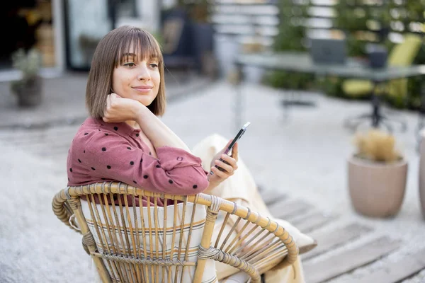 Young Woman Using Phone While Sitting Relaxed Chair Backyard Her — стоковое фото