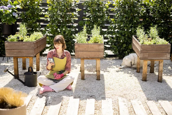 Mulher Usando Telefone Enquanto Sentado Relaxado Casa Horta Com Plantas — Fotografia de Stock