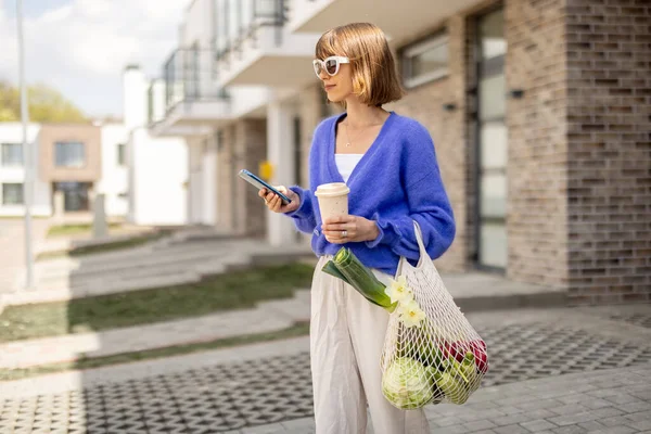 Woman Using Phone While Standing Mesh Bag Full Fresh Vegetables — Foto de Stock