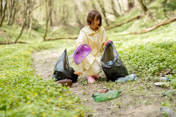 Koruyucu Elbiseli Genç Bir Kadın Ormanda Dağınık Plastik Çöpleri Topluyor — Stok fotoğraf