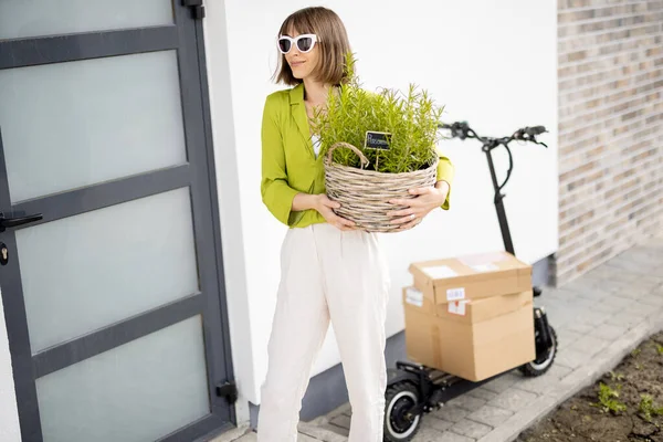 年轻时髦的女人提着装有迷迭香的篮子 乘电动车回家 可持续和生态友好型生活方式的概念 — 图库照片