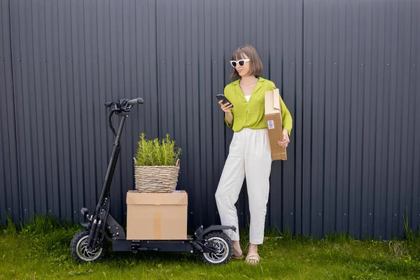 Young Woman Standing Phone Her Electric Scooter Parcels Flowerpot Gray — стоковое фото