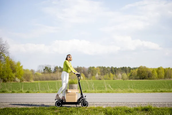 Jovem Mulher Dirigindo Scooter Elétrico Com Parcelas Vaso Flores Estrada — Fotografia de Stock