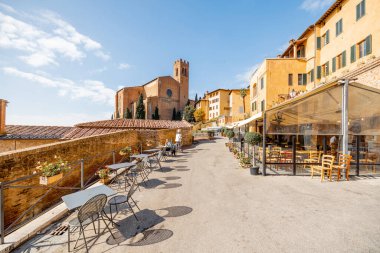 Siena 'da restoran masaları ve San Domenico bazilikasıyla caddeyi seyret. İtalya 'nın Toskana bölgesinde gezici işaretler
