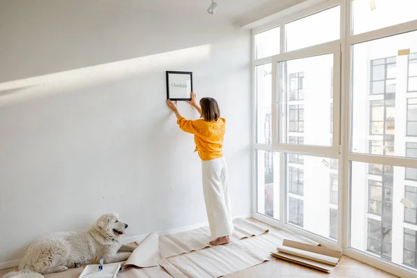 Young Woman Hanging Picture Frame Room Decorating Her Newly Renovated — Stockfoto