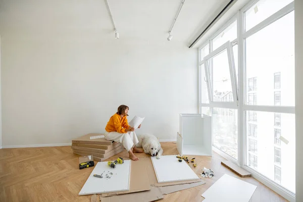 Young Woman Assembles Furniture Herself Sitting Dog Window Reading Manual — Stockfoto