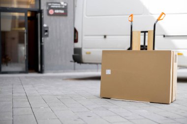 Folding furniture in cardboard boxes on a pushcart delivered by vehicle near building entrance. Concept of home delivery