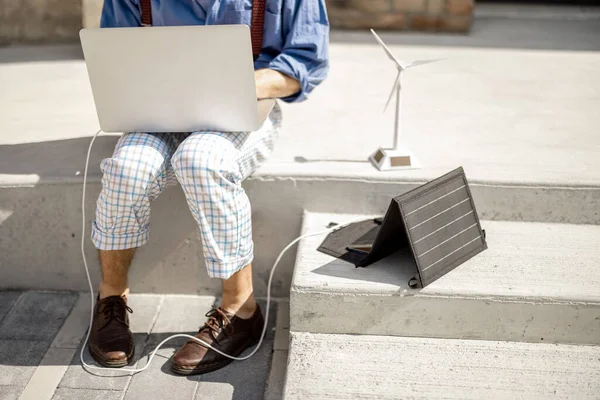 Stylowy Człowiek Pracuje Laptopie Ładuje Przenośnego Panelu Słonecznego Siedząc Ulicy — Zdjęcie stockowe