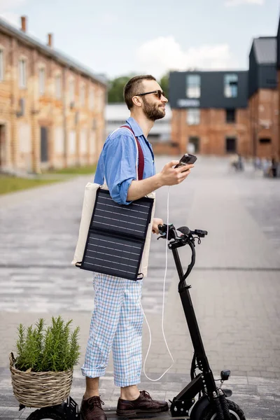 Stijlvolle Man Rijdt Elektrische Scooter Laadt Telefoon Met Zonnepaneel Beweging Rechtenvrije Stockafbeeldingen