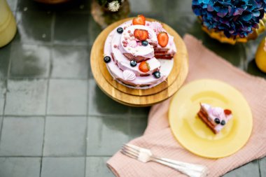 Beautiful tiled table served with festive berry cheesecake and decorated with flowers, view from above. Sweet holiday concept