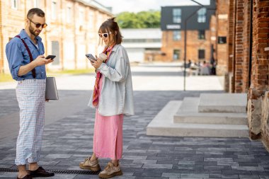 Genç ve şık bir çift kahve molası sırasında telefon başında sohbet ediyorlar. Genç hippiler ofisin yakınında birlikte takılıyor.