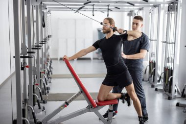 Rehabilitasyon uzmanının yardımıyla basınç azaltma simülatörleri üzerinde egzersiz yapan adam. Sağlık ve iyileşme için fizik tedavi kavramı. Geçmişin tedavisinde kineziyoloji fikri