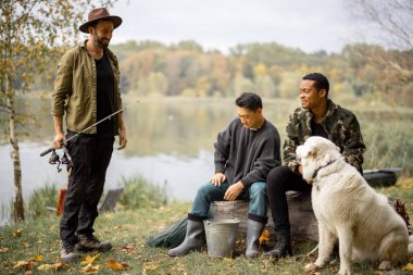 Çok ırklı erkek arkadaşlar dinleniyor ve doğada konuşuyorlar. Nehirde ya da göl kıyısında balık tutan adamlar. Boş zaman kavramı ve hafta sonu doğası. Arkadaşlık ve köpekle vakit geçirme fikri.