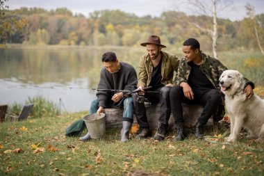 Çok ırklı erkek arkadaşlar dinleniyor ve doğada konuşuyorlar. Nehirde ya da göl kıyısında balık tutan adamlar. Boş zaman kavramı ve hafta sonu doğası. Arkadaşlık ve köpekle vakit geçirme fikri.