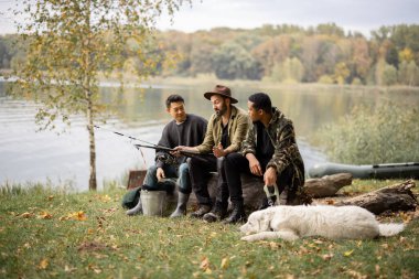 Çok ırklı erkek arkadaşlar dinleniyor ve doğada konuşuyorlar. Nehirde ya da göl kıyısında balık tutan adamlar. Boş zaman kavramı ve hafta sonu doğası. Arkadaşlık ve köpekle vakit geçirme fikri.