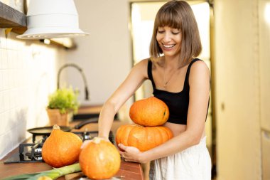 Young housewife carries pumpkin vegetables while cooking healthy food in kitchen. Concept of vegetarian food and autumn pumpkin menu