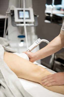 Applying vacuum roller massage to female leg using a special nozzle at beauty medical center, close-up. Concept of modern medical procedures for beauty