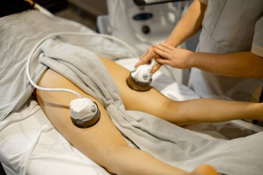 Applying vacuum roller massage to female leg using a special nozzle at beauty medical center. Concept of modern medical procedures for beauty