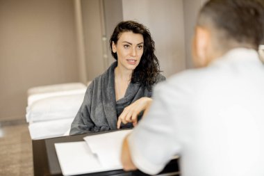 Woman in a bathrobe on appointment with senior therapist in luxury medical spa salon. Consultation with a doctor before beauty procedures