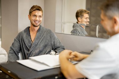 Man in a bathrobe on appointment with senior therapist in luxury medical spa salon. Consultation with a doctor before beauty procedures