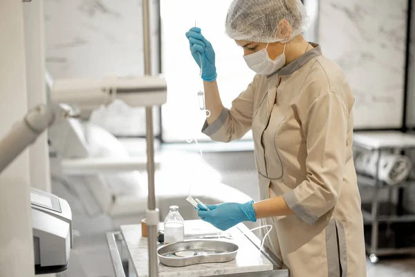 Nurse in face mask prepares needle and dropper for blood washing procedure at medical office