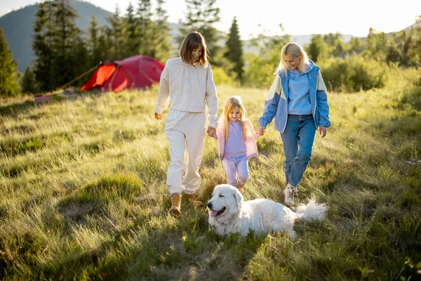 两个女人带着小女孩和白狗散步 快乐地在大自然中度过夏天 有小孩的同性恋家庭在山上旅行 — 图库照片