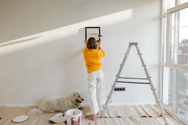 Young Woman Hanging Picture Frame Room Decorating Her Newly Renovated — kuvapankkivalokuva