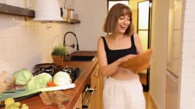 Genç kadın mutfakta sağlıklı salata pişirip yerken mutlu ve iyi hissediyor. Evde refah, diyet ve mutlu yaşam biçimi kavramı