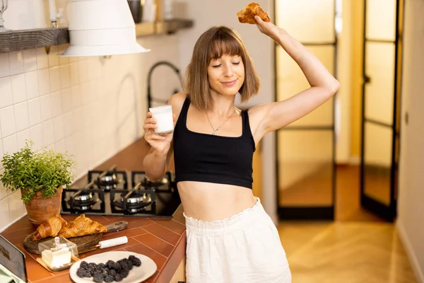 年轻妇女在现代化公寓的厨房里吃早饭时伸懒腰 健康的概念和睡后醒来 — 图库照片