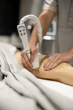 Applying vacuum roller massage to female leg using a special nozzle at beauty medical center, close-up. Concept of modern medical procedures for beauty