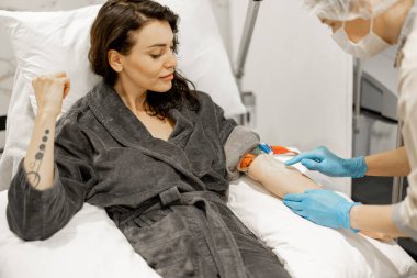Nurse makes an injection into a vein taking blood for tests or washing blood with a dropper for a woman at medical office