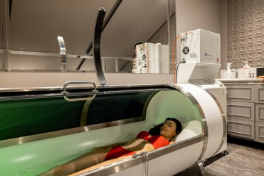Woman lying in oxygen capsule, having deep rest and recovery during the medical procedure of filling the body with oxygen