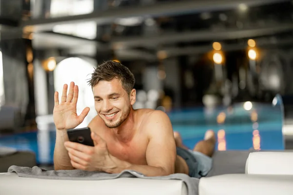 Man Rests Swimming Pool Indoors Talking Phone While Lying Relaxed — Stock fotografie
