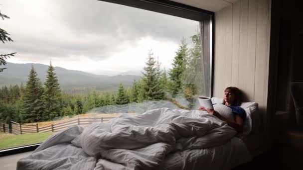Kobieta Czyta Książkę Leżąc Pokryta Kocem Parapecie Pięknym Widokiem Góry — Wideo stockowe