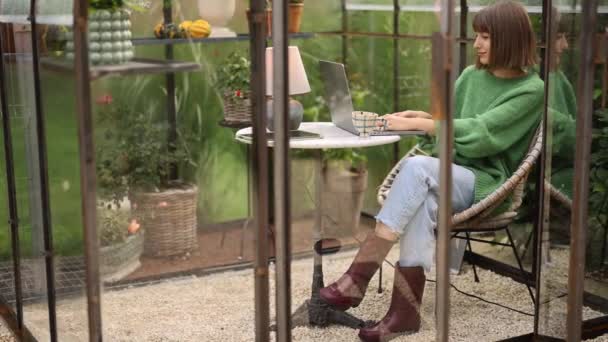 Mladá Žena Pracuje Notebooku Zatímco Sedí Kulatého Stolu Skleníku Rostlinami — Stock video
