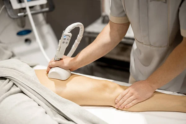 Applying vacuum roller massage to female leg using a special nozzle at beauty medical center, close-up. Concept of modern medical procedures for beauty