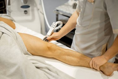 Applying vacuum roller massage on male leg using a special nozzle at beauty medical center, close-up. Concept of modern medical procedures for beauty