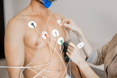 Torso of man athlete with electrodes, testing heart system on bike simulator