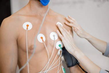 Torso of man athlete with electrodes, testing heart system on bike simulator