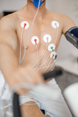 Torso of man athlete with electrodes, testing heart system on bike simulator