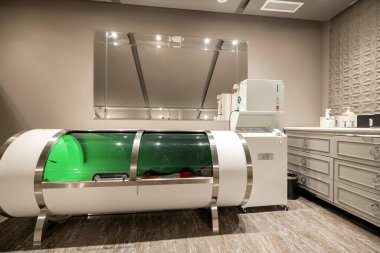 Woman lying in oxygen capsule, having deep rest and recovery during the medical procedure of filling the body with oxygen