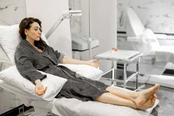 穿着浴衣的妇女正在等待血液洗洗和维生素氨化程序 或在医疗中心验血 躺在舒适的医疗沙发上休息 — 图库照片